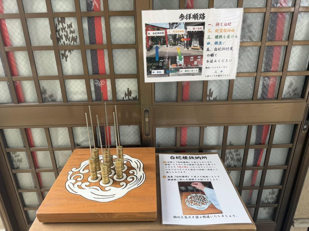 白蛇種銭と銭洗いの参拝方法を案内する掲示とつなぎ棒