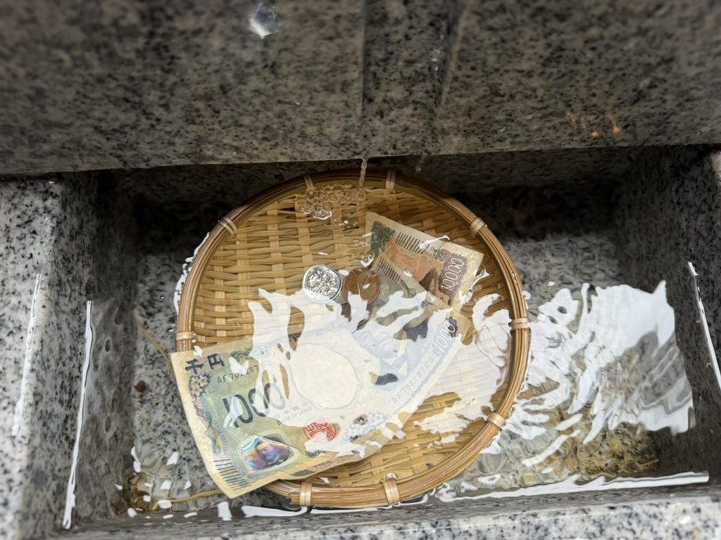 小網神社で銭洗いをする様子